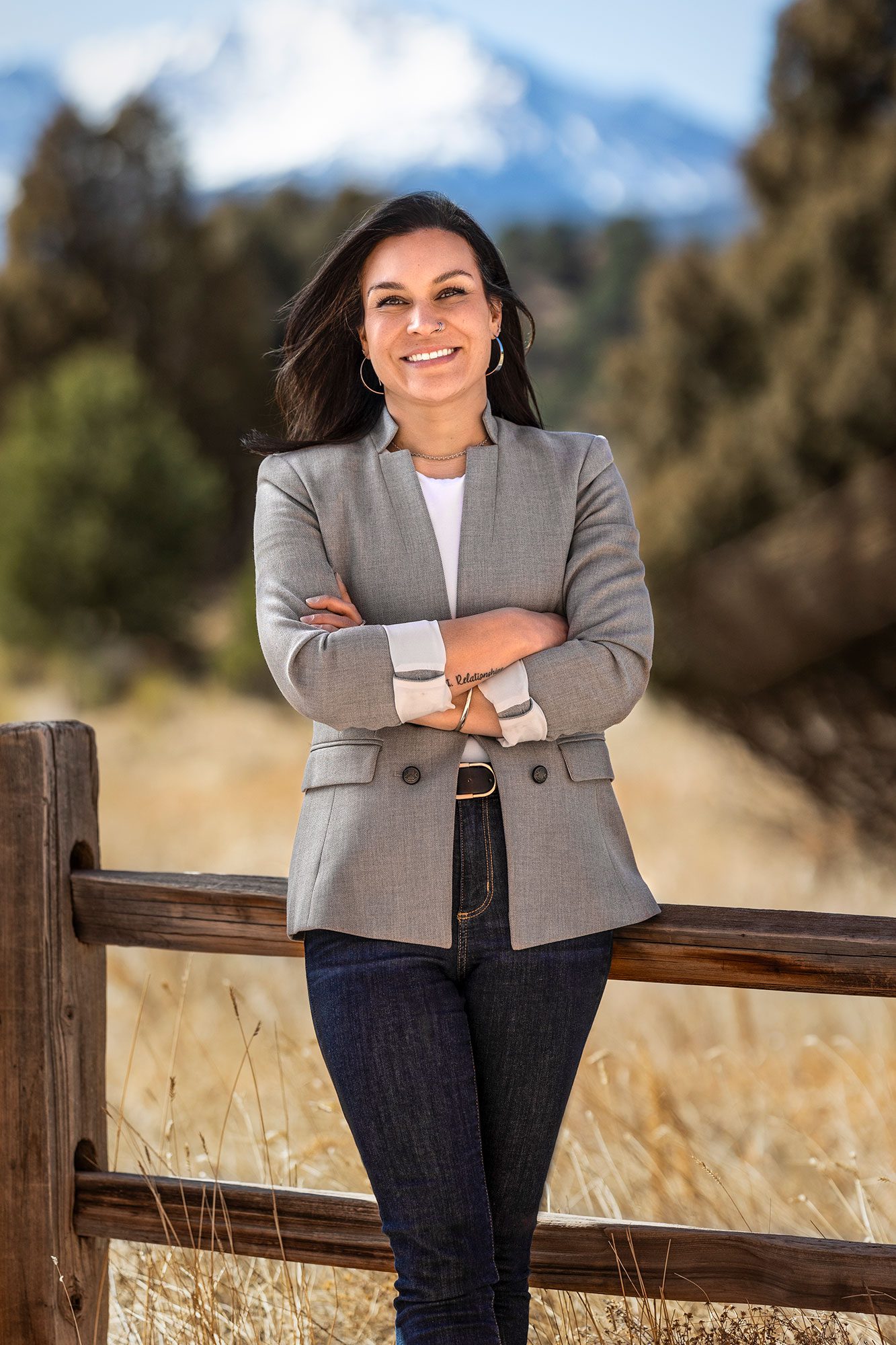 Professional headshot of Emily Moller leaning against a pole with blurred farmland in the background.